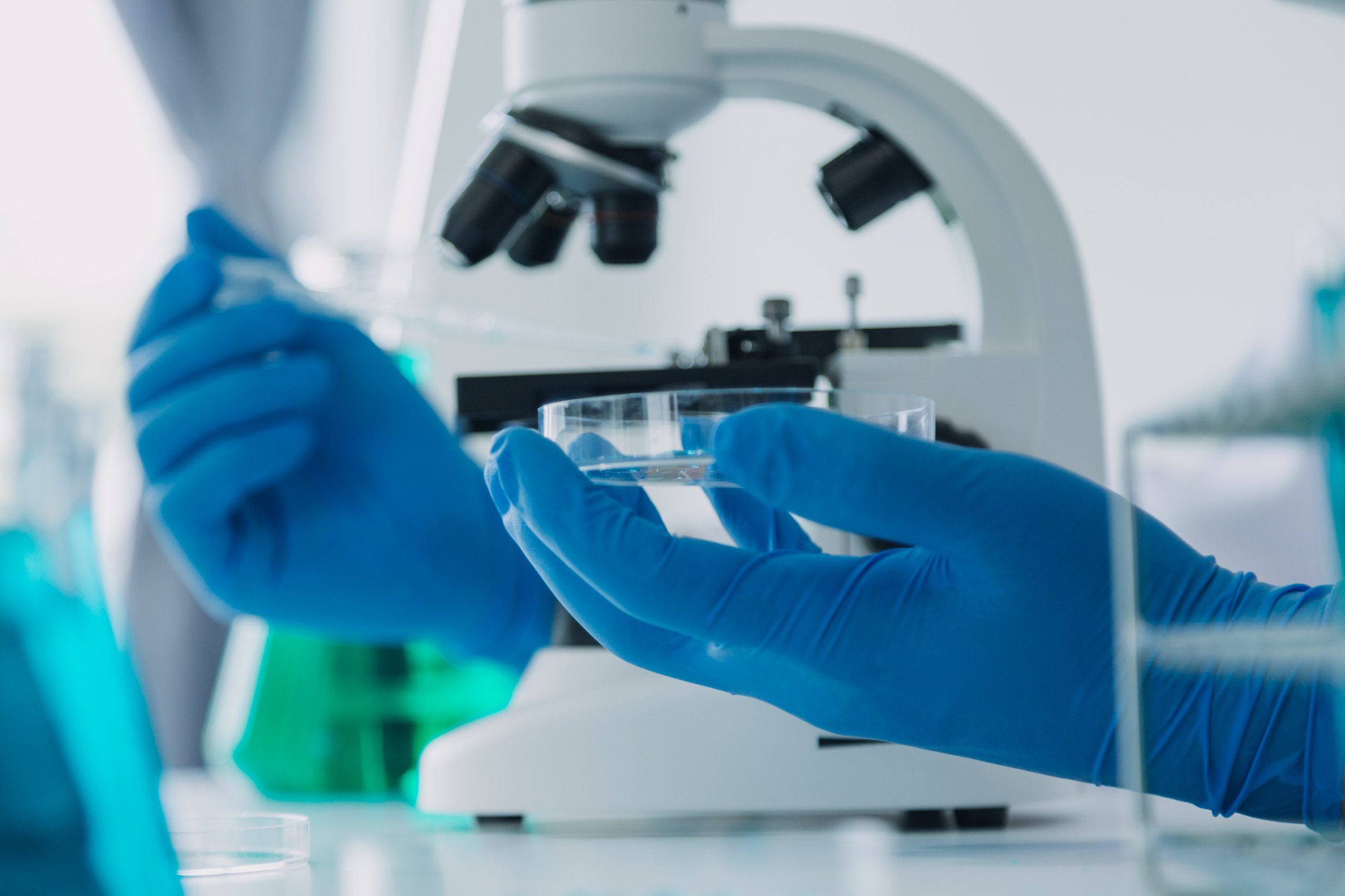 medical or scientific researcher researching and experimenting Multi-colored solution, vial and microscope In the laboratory or in the laboratory by wearing blue gloves and white clothing completely.